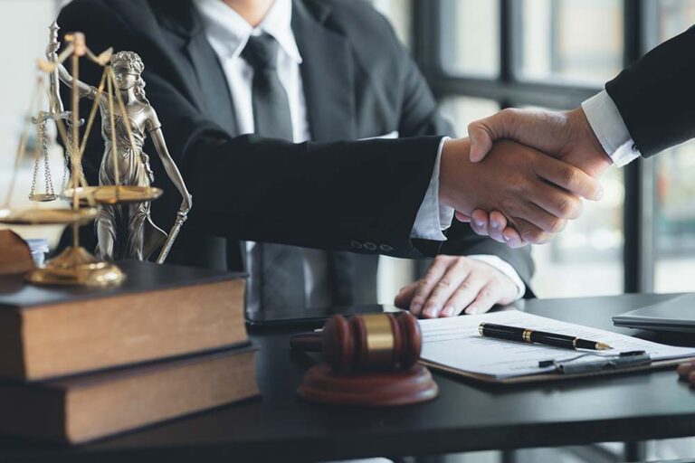 Commercial lawyers shaking hands over a desk
