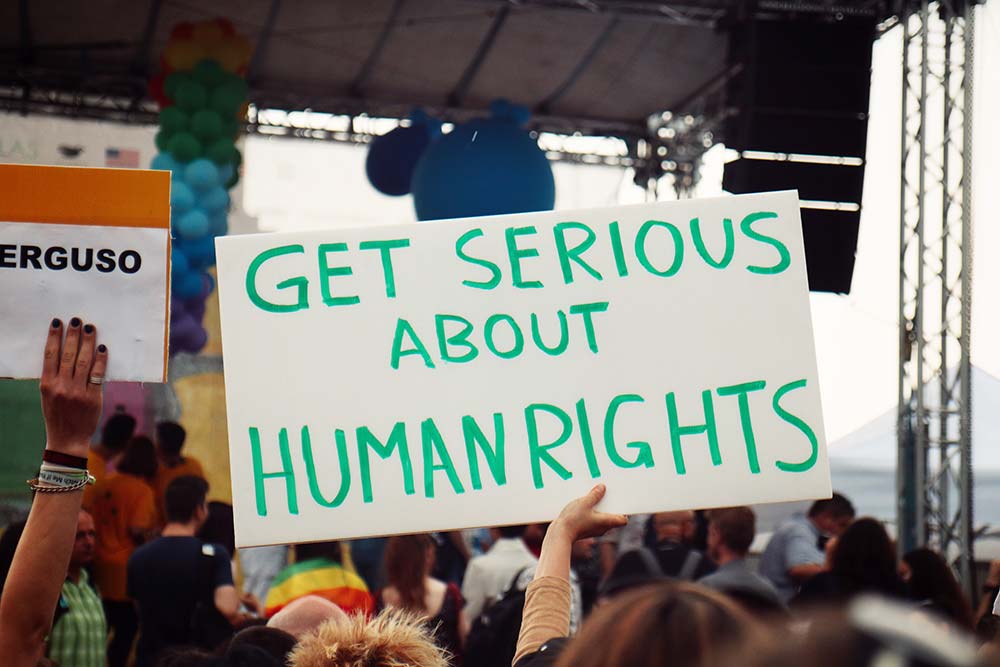 Human rights law - a protest where one of the protestors is holding up a sign saying get serious about human rights