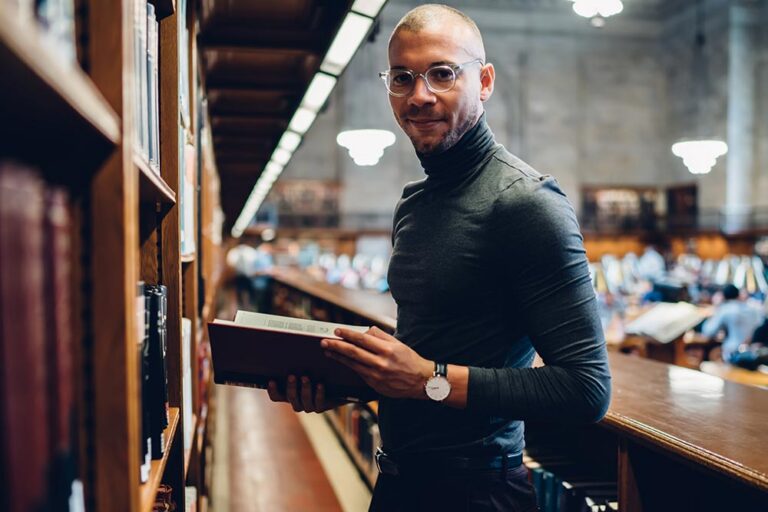 Man standing reading a law book in a law library