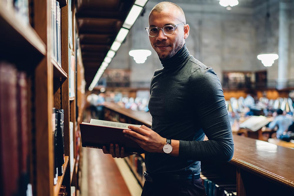 Man standing reading a law book in a law library